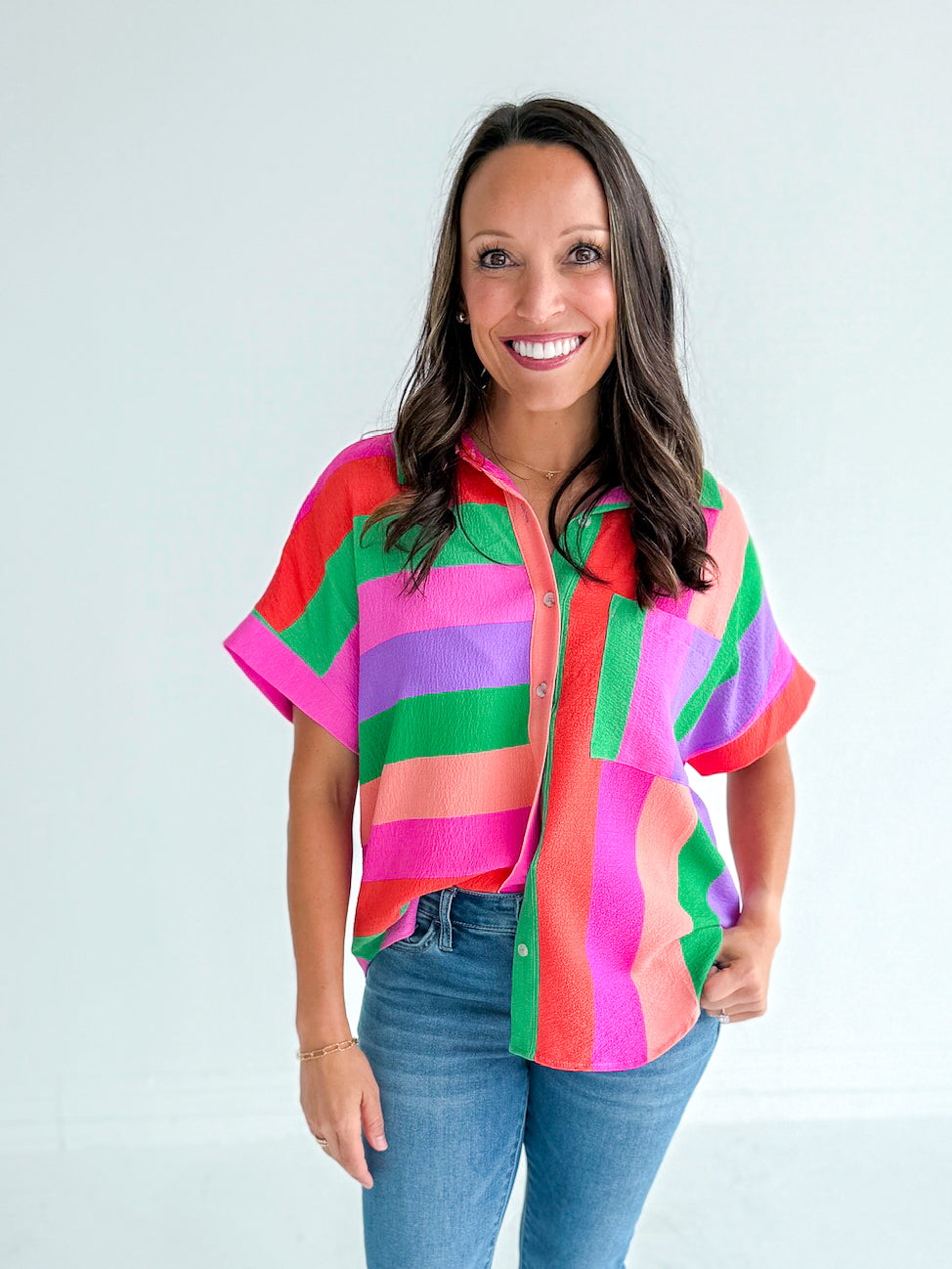 Woman wearing a colorful striped shirt and jeans on a white background